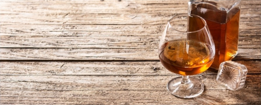 Cognacsglas bredvid en liten flaska cognac och isbit
